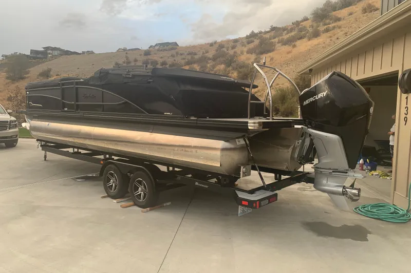 Slide: The Image of 2022 Barletta Corsa 25U pontoon boat on trailer, parked in driveway. - 2