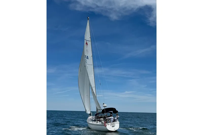 The Image of 1986 Catalina 34 sailboat cruising on open sea under clear blue sky. - 1