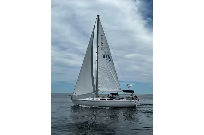 Slide: The Image of 1986 Catalina 34 sailboat gliding on calm waters under a cloudy sky. - 2