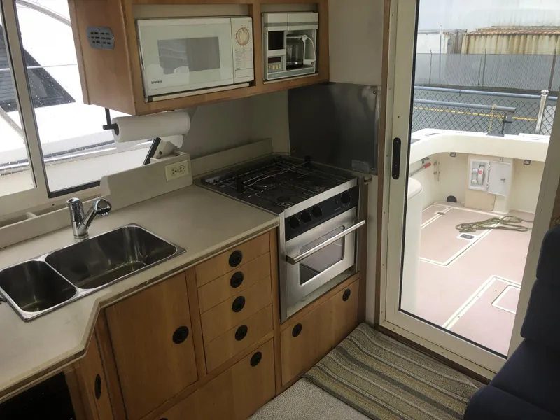 Slide: The Image of 2000 Albin 35 Tournament Express kitchen with stove, microwave, and sink, overlooking deck area. - 13