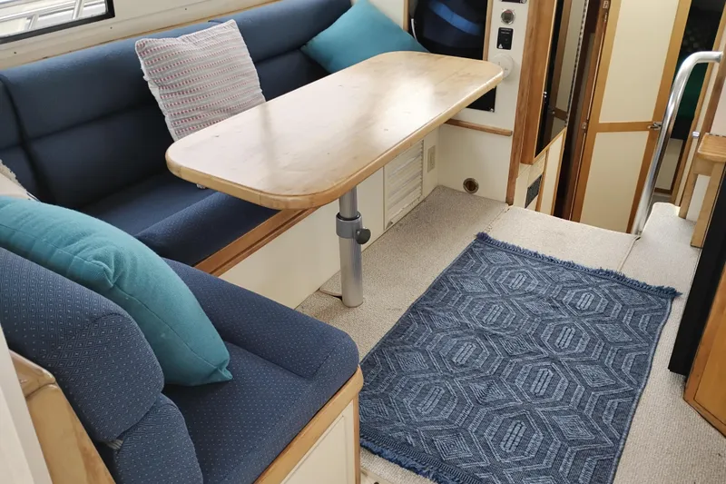 Slide: The Image of Interior of 2000 Albin 35 Tournament Express with blue seating, wooden table, and geometric rug. - 18