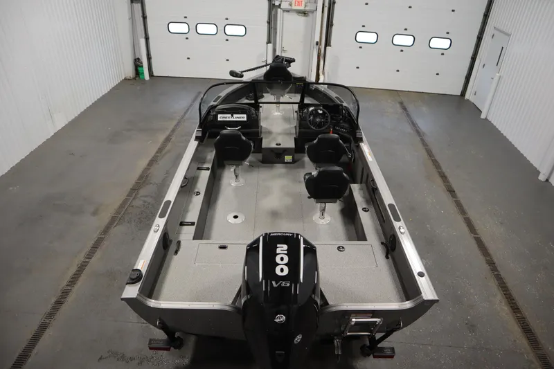 Slide: The Image of 2024 Crestliner 1950 Fish Hawk WT boat in a garage, featuring a powerful Mercury 200 engine. - 10