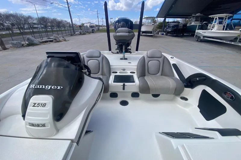 Slide: The Image of 2013 Ranger Z518 Intracoastal boat interior with seating and console, parked outdoors. - 12