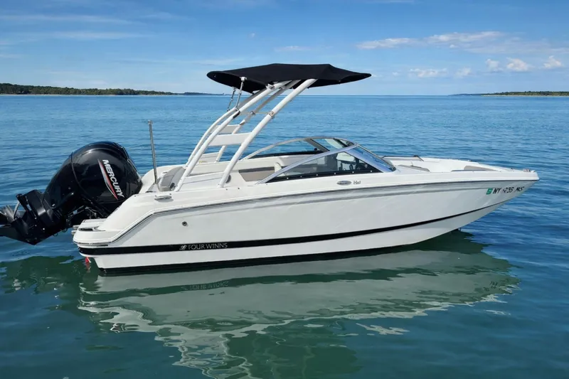The Image of 2021 Four Winns HD1 OB boat on calm blue water, featuring a sleek design and outboard motor. - 0