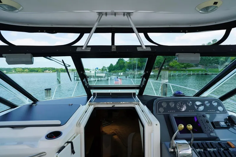 Slide: The Image of 2004 Tiara Yachts 2900 Open Classic cockpit view, showcasing dashboard and serene waterfront. - 27