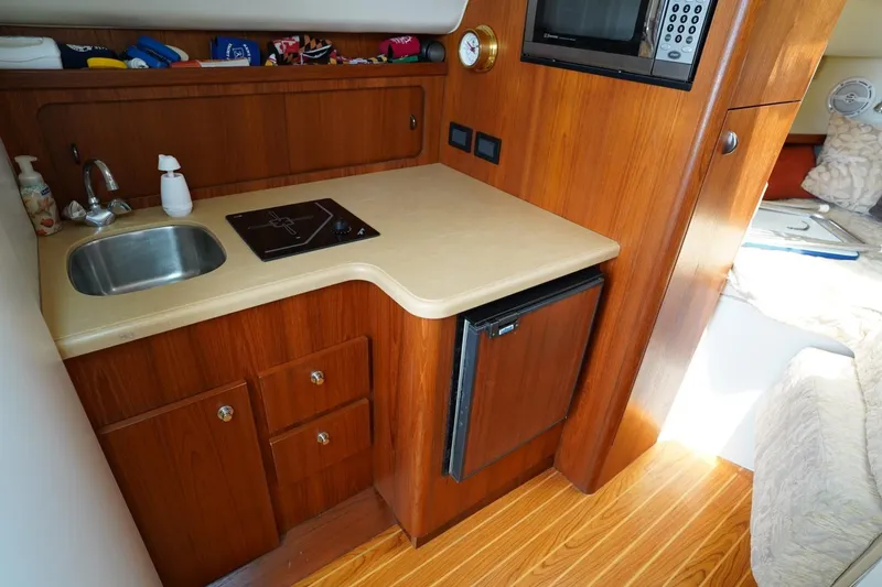 Slide: The Image of 2004 Tiara Yachts 2900 Open Classic interior with kitchenette, sink, stove, and microwave. - 35