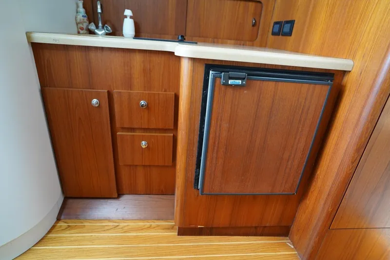 Slide: The Image of 2004 Tiara Yachts 2900 Open Classic interior with wooden cabinetry and compact fridge. - 37