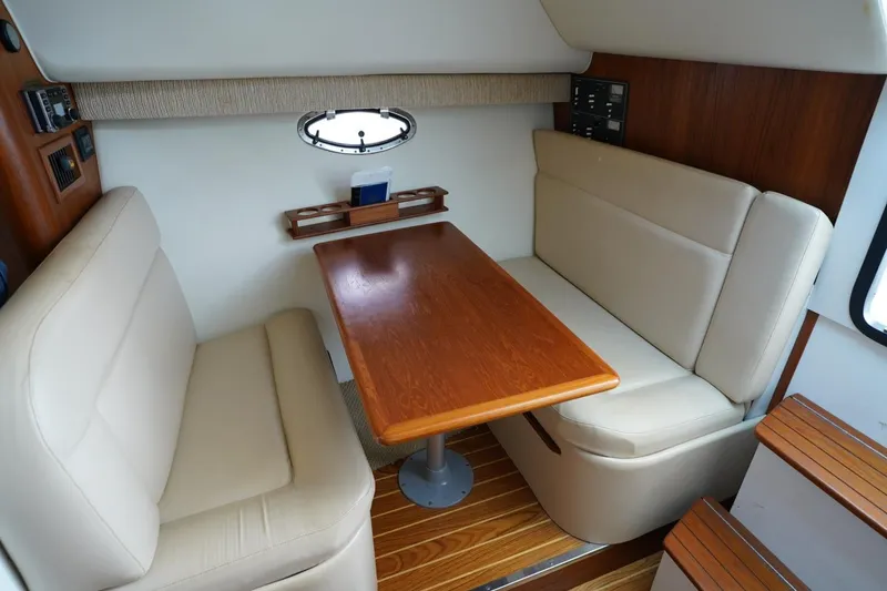 Slide: The Image of 2004 Tiara Yachts 2900 Open Classic interior with beige seating and wooden table. - 40