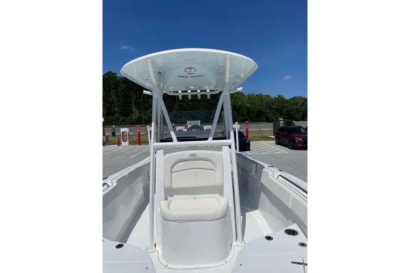 Slide: The Image of 2023 Sea Hunt Ultra 234 boat with T-top, parked outdoors under clear blue sky. - 5