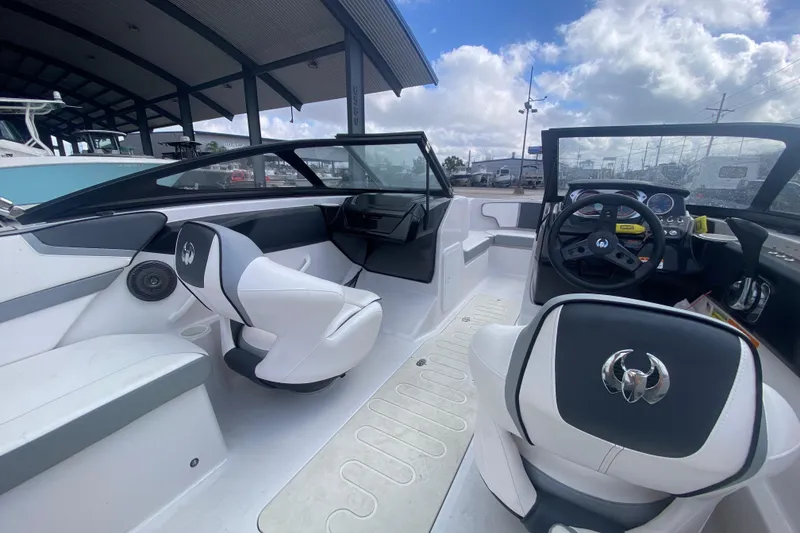 Slide: The Image of 2018 Scarab 215 G boat interior with modern seating and steering wheel under a cloudy sky. - 11
