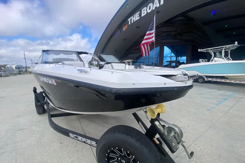 Slide: The Image of 2018 Scarab 215 G boat on trailer, displayed outdoors with American flag. - 6