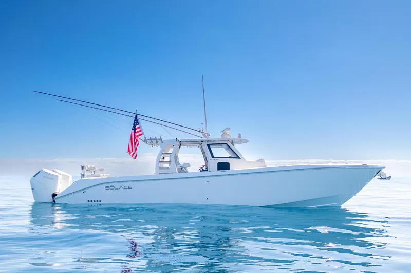 The Image of 2024 Solace 41 CS boat on calm ocean with American flag, clear blue sky. - 0