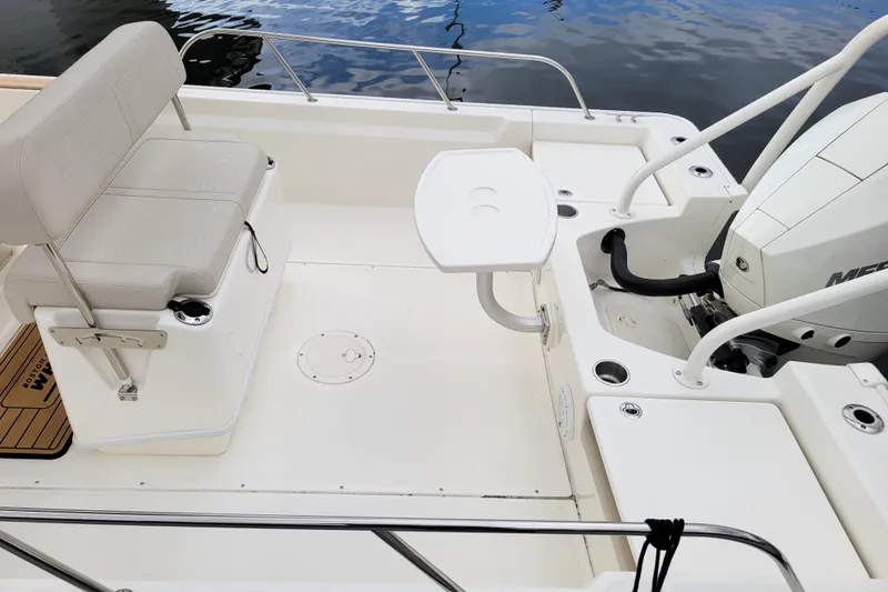 Slide: The Image of 2023 Boston Whaler 210 Montauk boat interior with seating and motor, docked on water. - 10