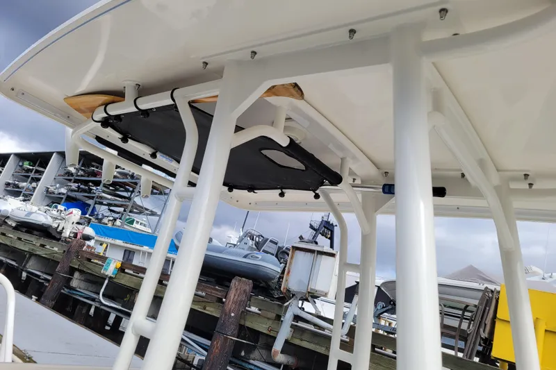 Slide: The Image of 2023 Boston Whaler 210 Montauk boat docked, showcasing sturdy frame and overhead structure. - 19