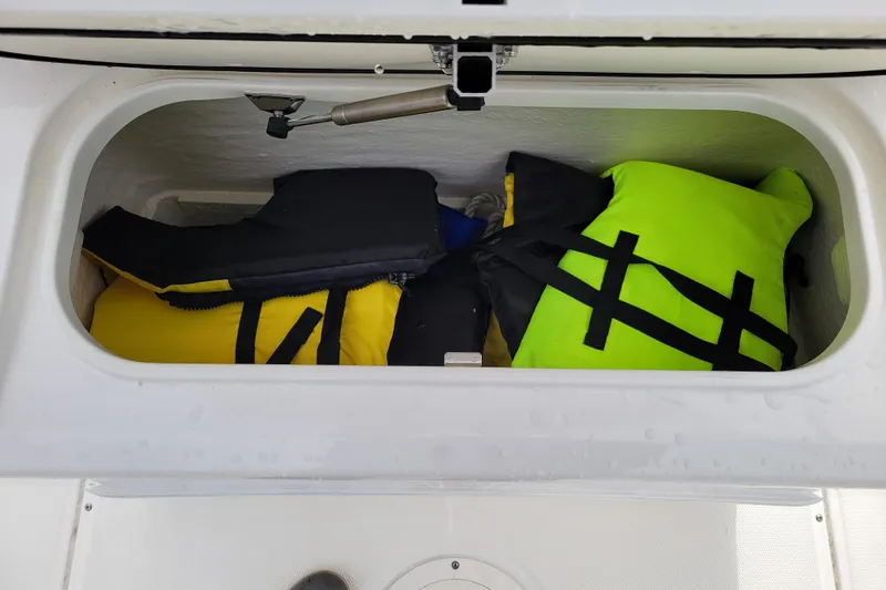 Slide: The Image of Storage compartment with life jackets on a 2023 Boston Whaler 210 Montauk boat. - 25