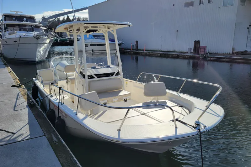 Slide: The Image of 2023 Boston Whaler 210 Montauk boat docked in a marina under clear skies. - 6