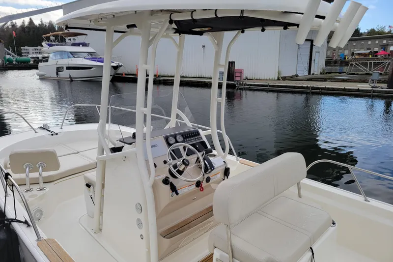 Slide: The Image of 2023 Boston Whaler 210 Montauk boat interior at marina, featuring helm and seating. - 9