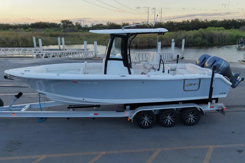 Slide: The Image of 2023 Sea Hunt Ultra 265 SE boat on trailer by waterfront at sunset. - 2