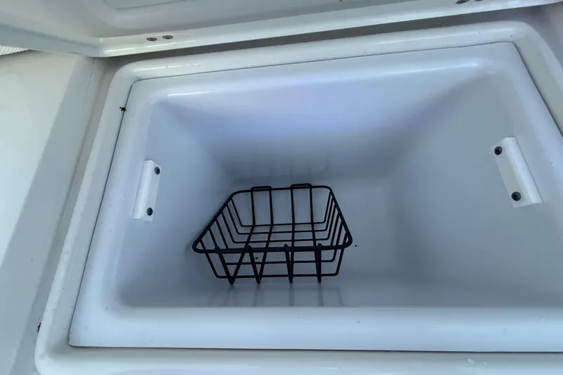 Slide: The Image of 2023 Sea Hunt Ultra 265 SE cooler compartment with wire basket. - 26