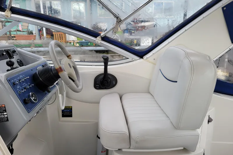 Slide: The Image of 2004 Bayliner 285 boat cockpit with steering wheel and white captain's seat. - 10
