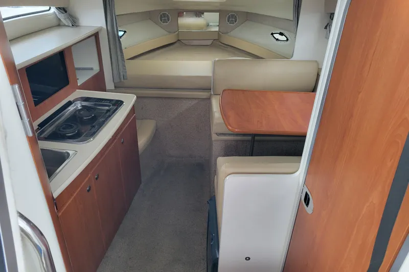 Slide: The Image of Interior of 2004 Bayliner 285 boat with striped bedding and wooden dining area. - 15