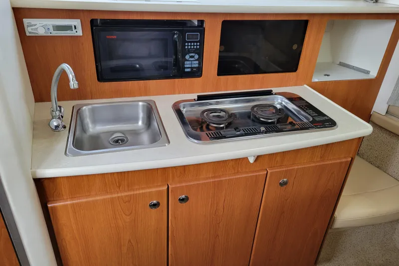 Slide: The Image of 2004 Bayliner 285 boat kitchen with sink, microwave, and wooden countertop. - 16