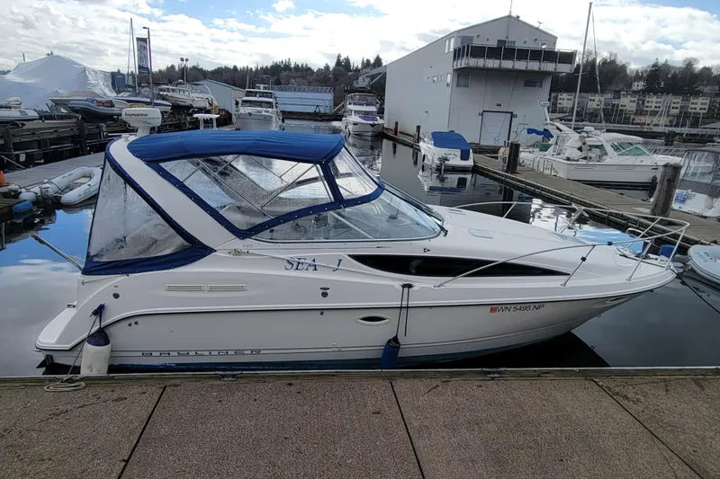 Slide: The Image of 2004 Bayliner 285 boat docked at marina with blue canopy and clear windows. - 2