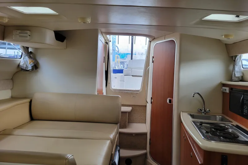 Slide: The Image of Interior of a 2004 Bayliner 285 boat featuring a kitchenette and seating area. - 24