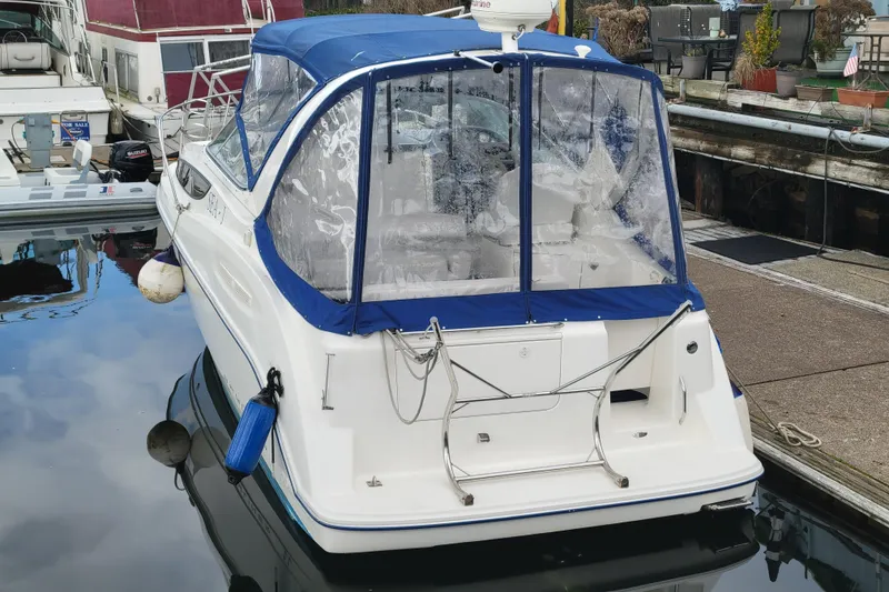 Slide: The Image of 2004 Bayliner 285 boat docked with blue canopy and clear windows. - 4