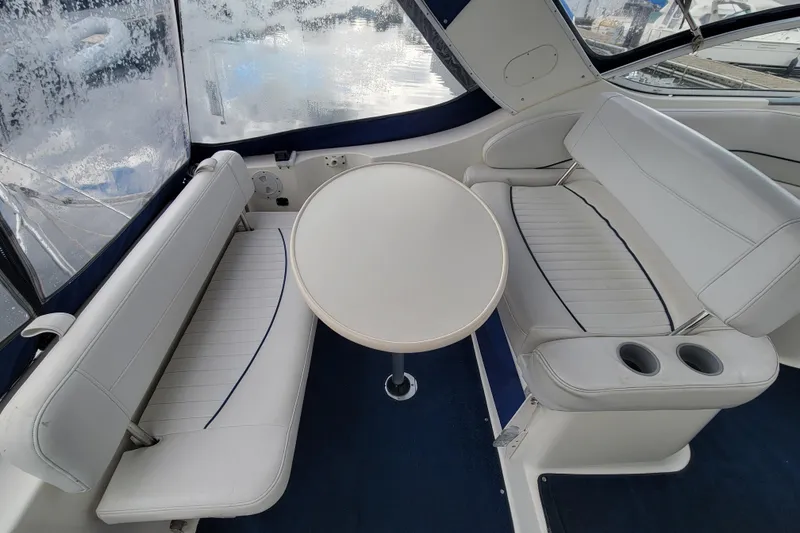 Slide: The Image of 2004 Bayliner 285 boat interior with white seating and round table. - 7