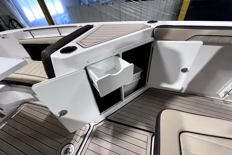 Slide: The Image of 2023 Yamaha Boats 255 FSH Sport E interior storage compartment with open doors and seating. - 28