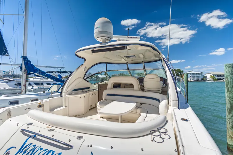 Slide: The Image of 2004 Sea Ray 420 Sundancer yacht docked, featuring spacious seating and clear blue skies. - 13