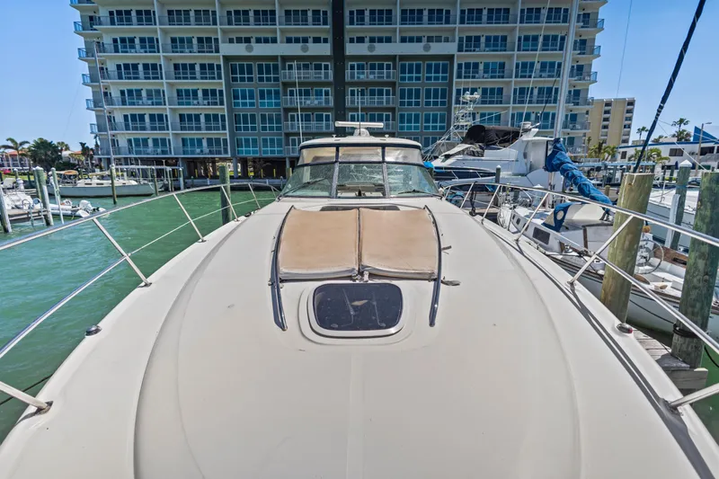 Slide: The Image of 2004 Sea Ray 420 Sundancer yacht docked at marina, with modern building backdrop. - 56