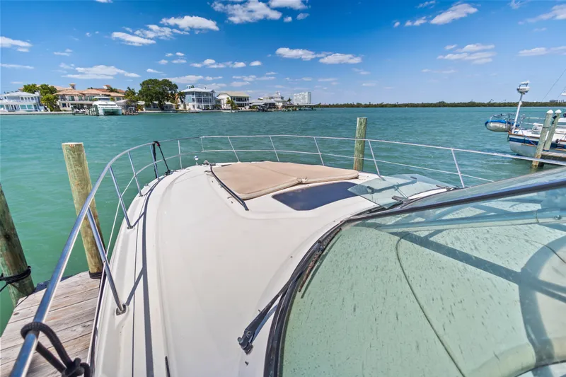 Slide: The Image of 2004 Sea Ray 420 Sundancer yacht docked by waterfront homes under blue sky. - 57