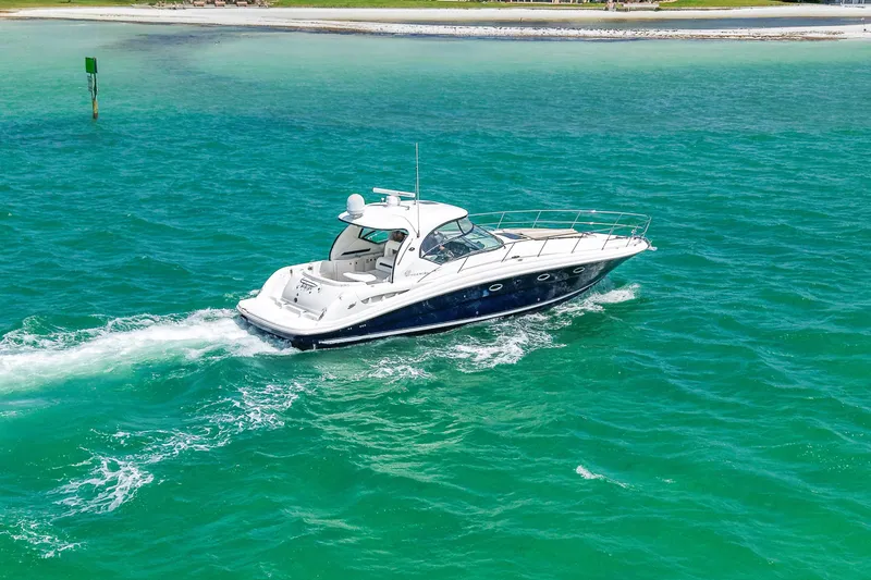 Slide: The Image of 2004 Sea Ray 420 Sundancer cruising on turquoise waters near a sandy shoreline. - 6