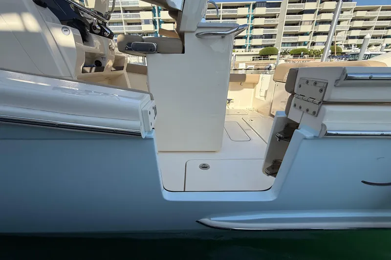Slide: The Image of 2024 Scout 260 LXF boat interior with seating and control panel, docked near buildings. - 10