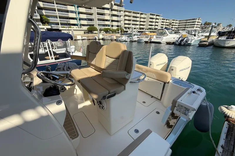 Slide: The Image of 2024 Scout 260 LXF boat interior with dual Mercury engines in a marina setting. - 18