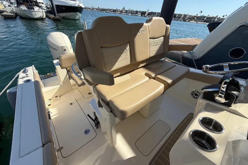 Slide: The Image of 2024 Scout 260 LXF boat interior with tan seating and Mercury engine, docked at marina. - 19