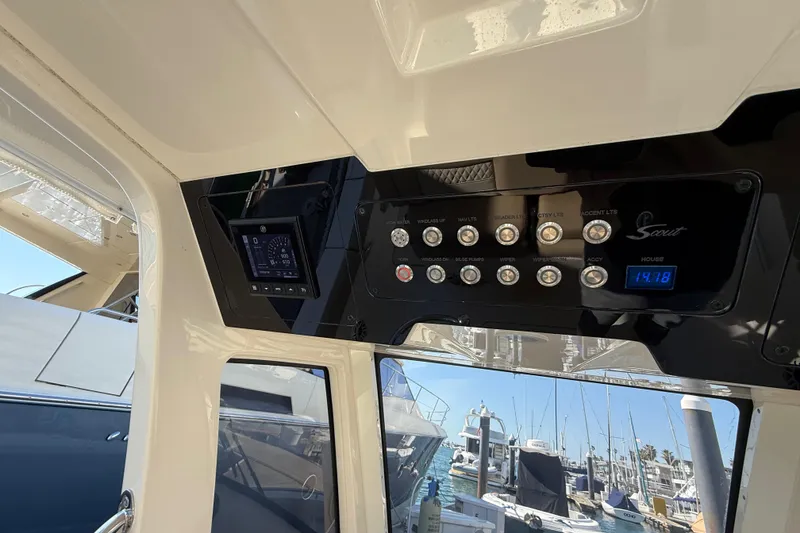 Slide: The Image of 2024 Scout 260 LXF boat dashboard with control panel and marina view. - 23