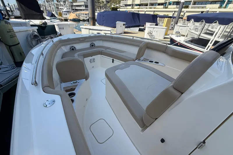 Slide: The Image of 2024 Scout 260 LXF boat interior with beige seating and cup holders at a marina. - 25