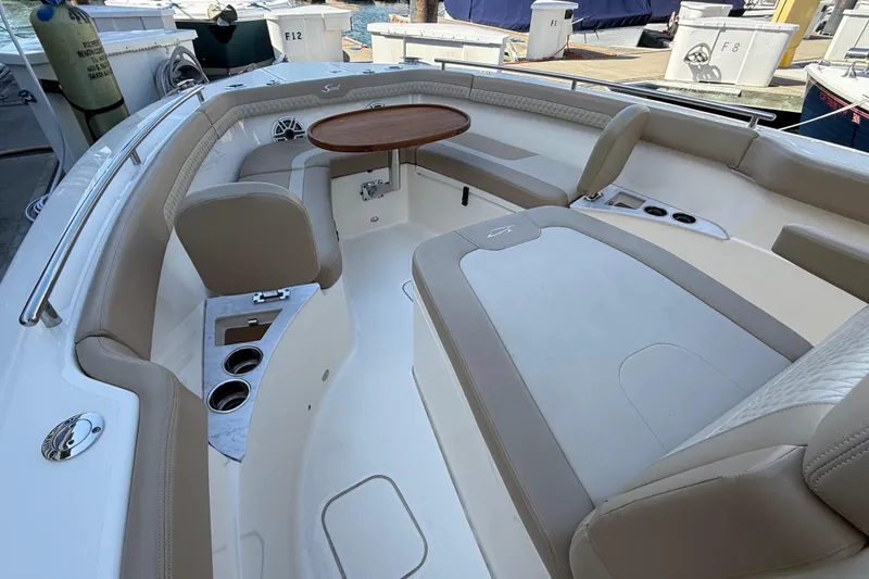 Slide: The Image of 2024 Scout 260 LXF boat interior with seating and table, docked at marina. - 26