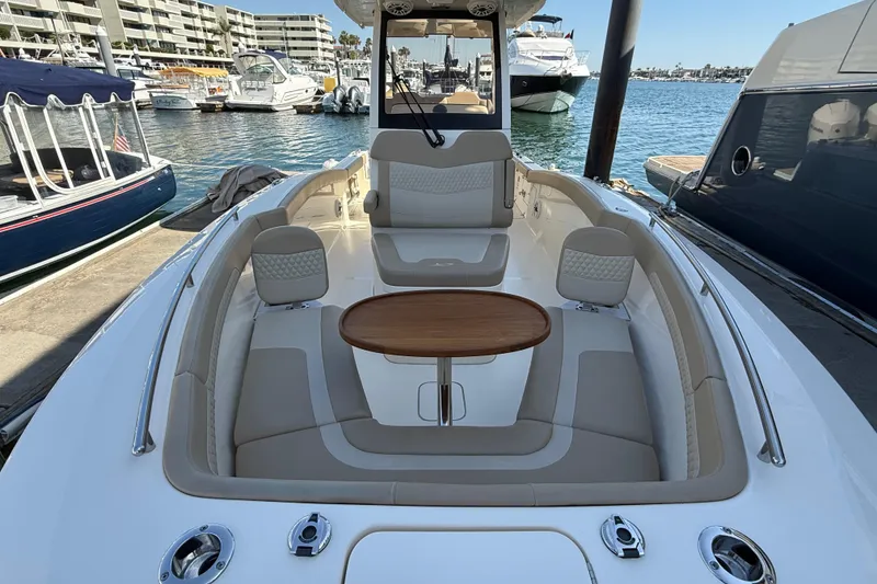 Slide: The Image of 2024 Scout 260 LXF boat interior with seating and wooden table, docked at marina. - 28