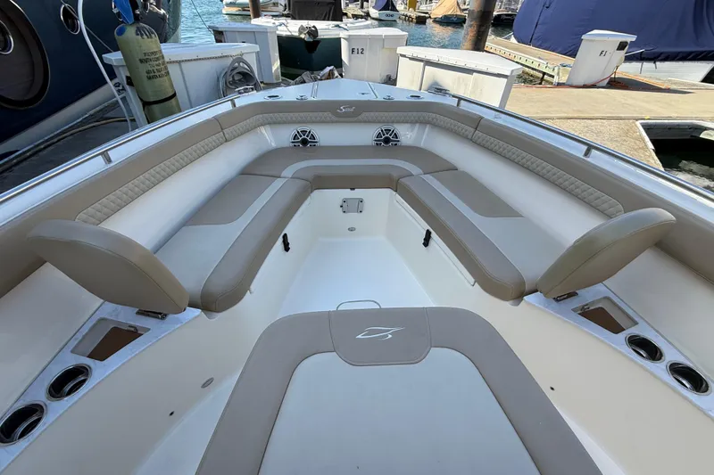 Slide: The Image of 2024 Scout 260 LXF boat interior with beige seating and cup holders at a marina. - 33