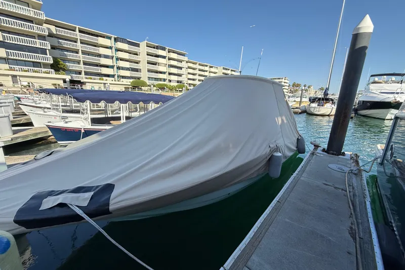 Slide: The Image of Covered 2024 Scout 260 LXF boat docked at marina with modern buildings in background. - 41