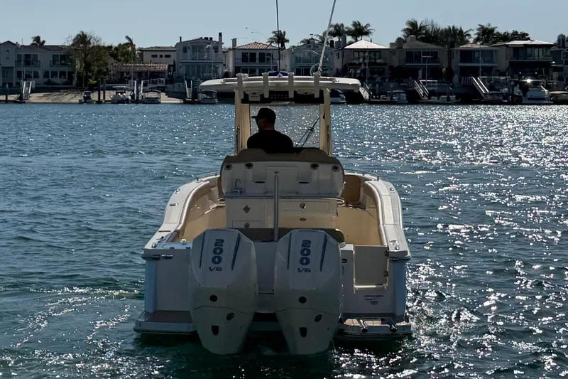 Slide: The Image of 2024 Scout 260 LXF boat cruising on a sunny waterfront with houses in the background. - 6