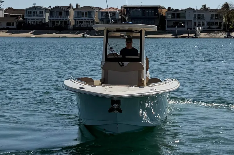 Slide: The Image of 2024 Scout 260 LXF boat cruising on a sunny waterfront with houses in the background. - 7