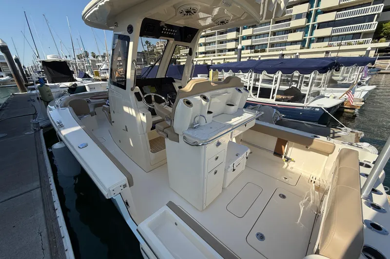 Slide: The Image of 2024 Scout 260 LXF boat docked at marina, showcasing spacious deck and seating area. - 9