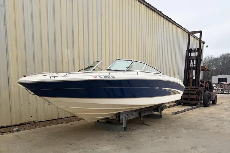 The Image of 2000 Sea Ray 230 Signature boat on a trailer near a large building. - 0