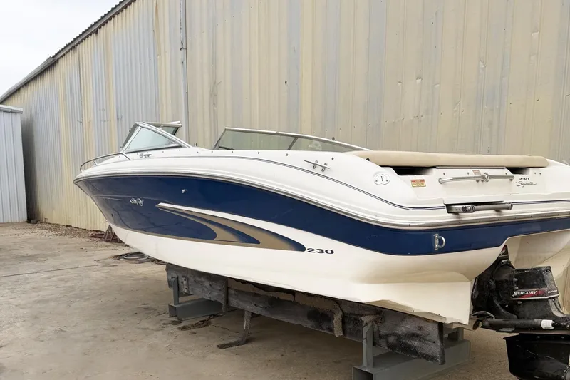 Slide: The Image of 2000 Sea Ray 230 Signature boat with blue and white hull, stored outdoors. - 1