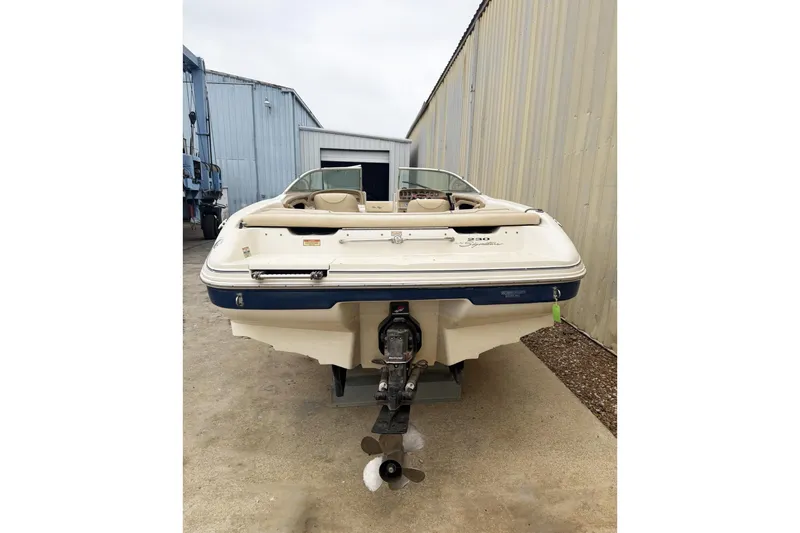 Slide: The Image of 2000 Sea Ray 230 Signature boat, rear view, parked near industrial buildings. - 4